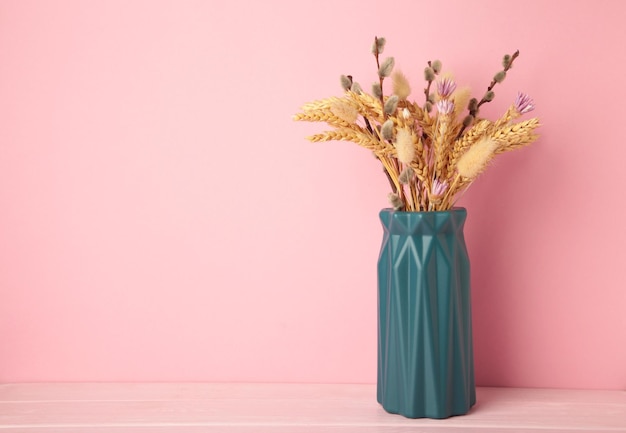 Trockene Blume in einer Vase auf rosa Hintergrund