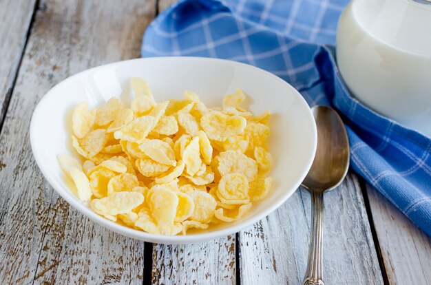 Trockene Cornflakes in weißer Platte, Flasche mit Milch