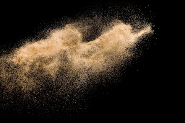 Foto trockene flusssand-explosion. goldener farbiger sandspritzen agianst dunkler hintergrund.