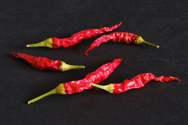 Trockene ganze Chilischoten auf schwarzem Tisch verstreut