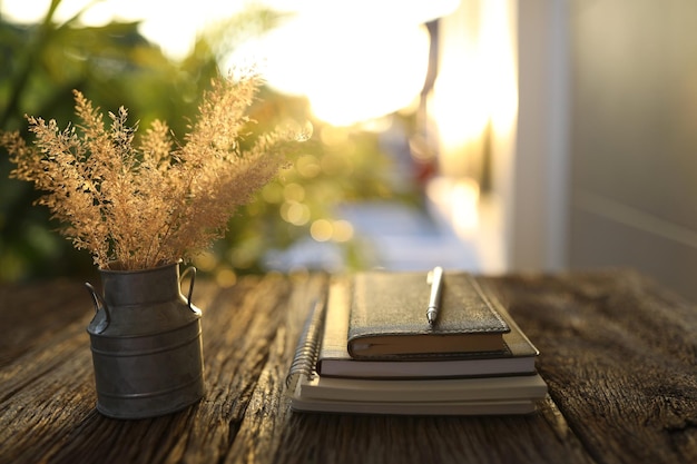 Trockene Grasblume in rostfreier Vase und Notizbüchern