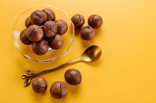 Trockene Macadamianüsse auf einer Untertasse auf gelbem Hintergrund