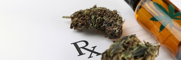 Trockene Marihuana-Blätter und Cannabis-Ölglas liegen auf ärztlicher Verschreibung in der Nähe