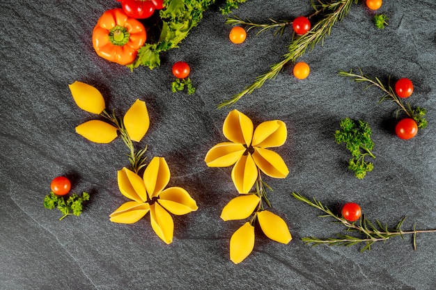 Trockene Muschelnudeln wie eine Blume mit Kirschtomaten und Paprika.