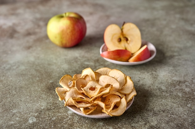 Trockene Äpfel-Chips-Scheiben und Apfelfrüchte auf rustikalem Holzhintergrund Nahaufnahme selektiver Fokus