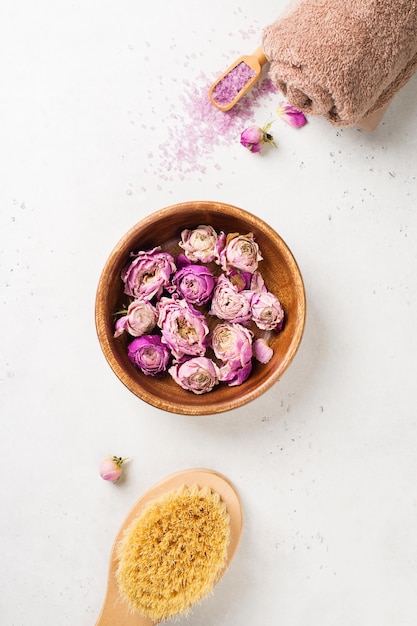 Trockene Rosenblüten bürsten Handtuch und rosa Salz Wellness Spa und Körperpflege flach legen Konzept auf weißem Hintergrund kopieren Raum Draufsicht