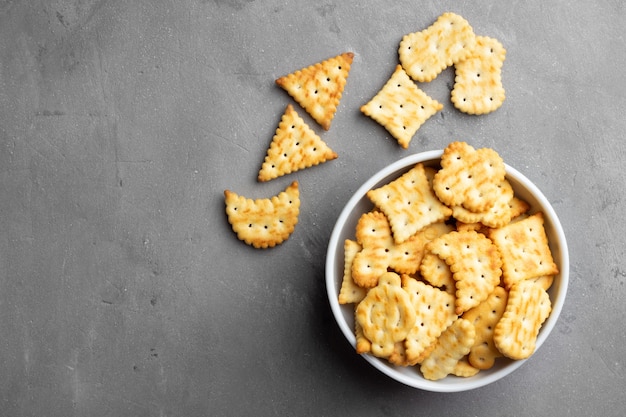 Trockene salzige Crackerplätzchen auf grauem Steinhintergrund.