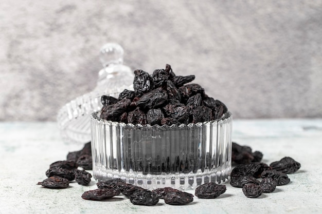 Trockene schwarze Trauben auf Steinhintergrund Trockene Trauben in Glasschüssel Nussarten Gesundes Essen aus der Nähe