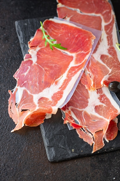 Trockener Jamon italienischer Schinken Serrano Bellota Crudo oder Parmaschinkenportion auf dem Tisch