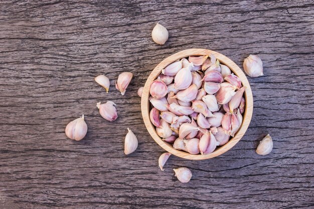 Trockener Knoblauch setzte in hölzerne Schüssel auf alten hölzernen Hintergrund