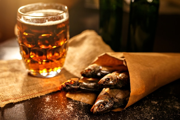 Trockenfisch- und Weinleseglas Bier auf einer schwarzen Oberfläche