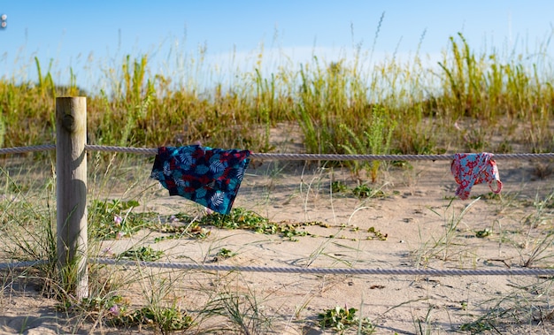 Trocknen Sie die Badeanzüge auf dem Zaun nach einem Bad im Meer