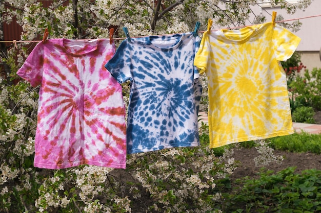 Trocknen von drei bunten T-Shirts im Tie-Dye-Stil