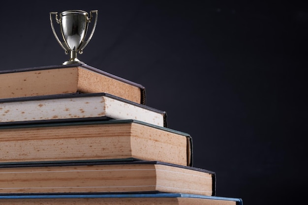 Foto trofeo y pila de libros contra la pizarra