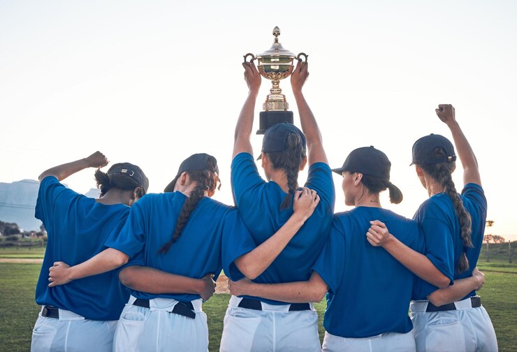 Foto troféu de beisebol e equipe comemoram vitória com mulheres ao ar livre em campo para competição esportiva atrás de atleta profissional ou grupo de jogadores de softball mostram prêmio de campeão ou conquista em um jogo