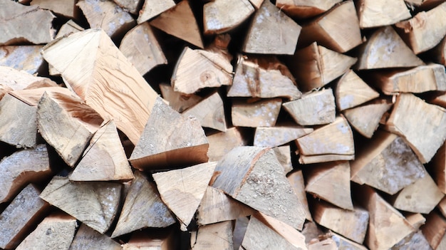 Un tronco de madera cortada cuidadosamente doblado. El fuego se está derritiendo. Leña apilada una encima de la otra. La leña se recolecta para calentar en climas fríos. Textura de fondo de leña seca apilada.