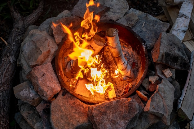 Troncos de abedul ardiendo en una fogata rodeada de piedras