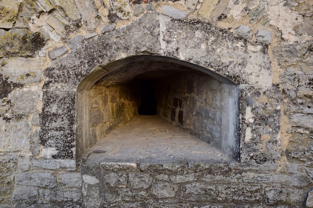 Tronera para disparar en el grueso muro de una antigua fortaleza o castillo. Cubierto con piedra en bruto