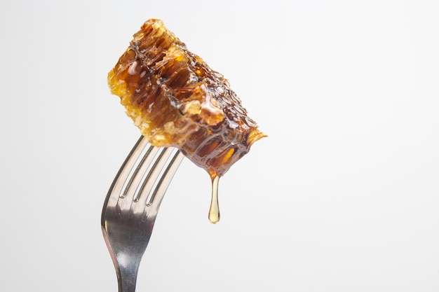 Tropfen frischen Honigs tropfen von Wachshonig auf eine Tischgabel. Vitaminernährung und Bienenprodukt