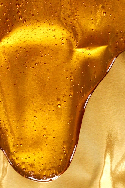 Tropfen Sie Honig mit Blasen auf einem goldenen Hintergrund