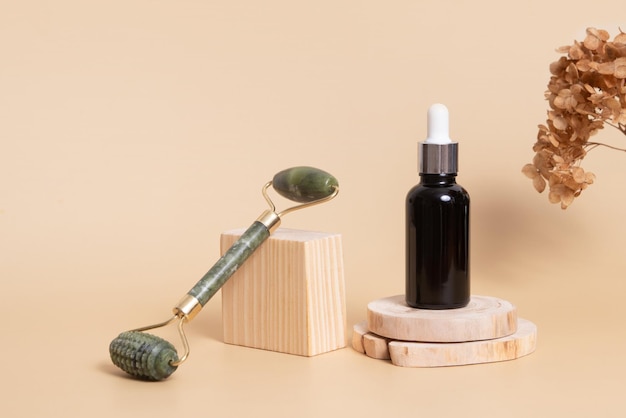 Tropfflasche mit kosmetischem Öl und Gesichtsmassagegerät auf Holzpodesten Gesichtspflegekonzept im rustikalen Stil