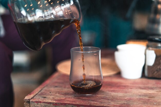 Tropfkaffee, Barista gießt Wasser auf Filterboden mit Filter, kocht Kaffee