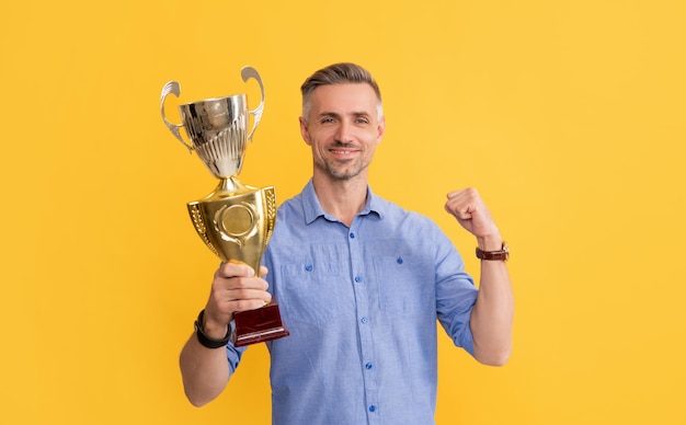 Trophäe und Prestige. Preis bekommen. Kerl feiert den Sieg. Inspiration und Motivation. Fröhlicher reifer Mann hält goldene Tasse. Leistungspreis. Motivation für unternehmerischen Erfolg.