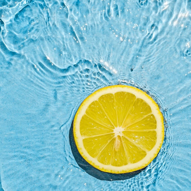 Trópicos naranja verano vegetariano limón jugoso brillante en agua azul de verano transparente con movimiento de onda