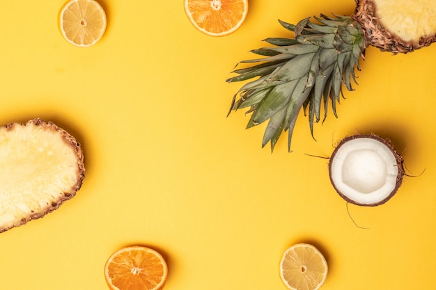 Tropische Ananas, Orangen, Zitrone und Kokosnuss auf einem Pastellhintergrund.