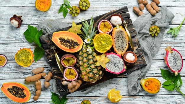 Tropische Früchte auf weißem Hintergrund: Papaya, Mangostan, Kaktusfrucht, Pytahaya, Ananas. Ansicht von oben. Freier Platz für Text.