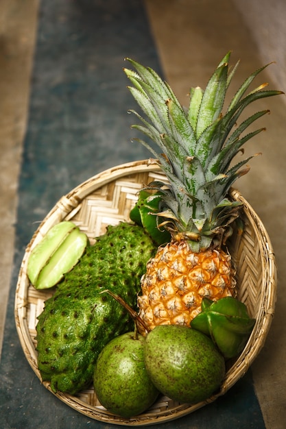 Tropische Früchte in einem Weidenkorb auf Betonboden