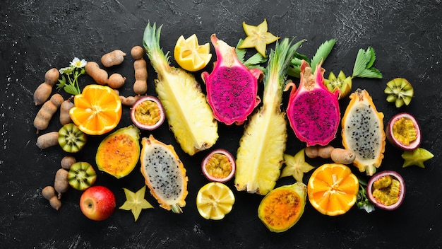 Foto tropische früchte passionsfrucht ananas drachenfrucht kiwi und kaktus auf schwarzem hintergrund draufsicht freier platz für text