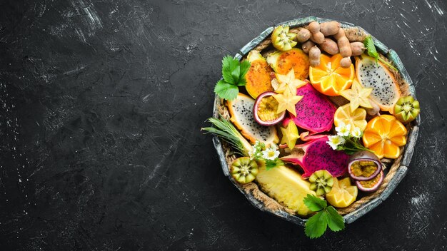 Tropische Früchte Passionsfrucht Ananas Drachenfrucht Kiwi und Kaktus auf schwarzem Hintergrund Oberseite Freier Platz für Text