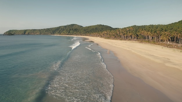 Tropische seelandschaft der ozeanbuchtantenne. touristen walzen am sandstrand. berg mit tropischen palmen