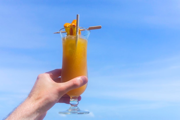 Tropischer Cocktail mit Orange gegen blauen Himmel