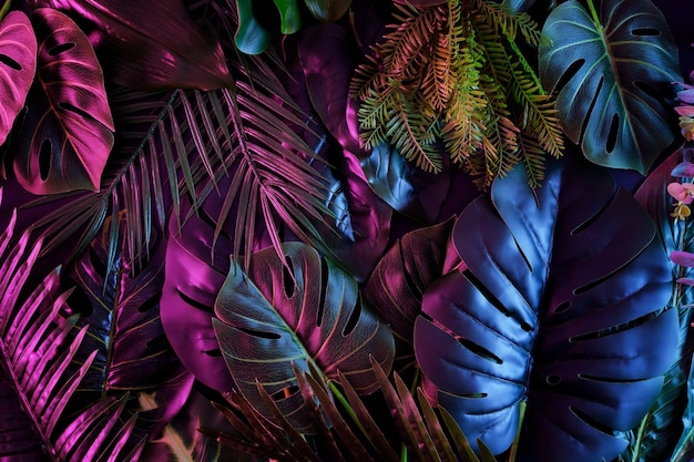 Tropischer dunkler Trenddschungel in neonbeleuchteter Beleuchtung. Exotische Palmen und Pflanzen im Retro-Stil.