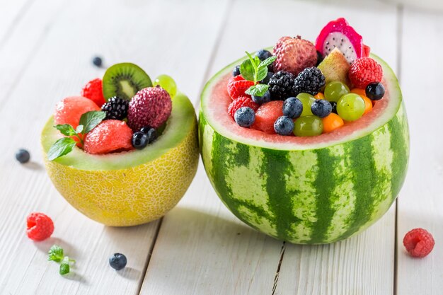 Tropischer Fruchtsalat in Wassermelone und Melone auf weißem Tisch