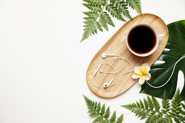 Tropischer Öko-Schreibtisch mit Kopfhörern und Kaffee