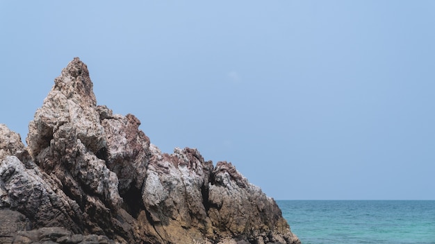 Tropischer Strand-, Felsen- und Sandhintergrund mit blauem Himmel.