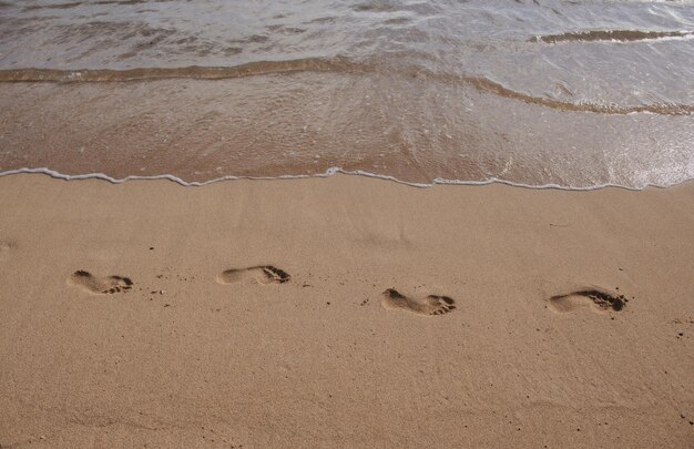 Tropisches Meerwasser, das auf den weißen Strandsand mit Fußabdruck kommt.