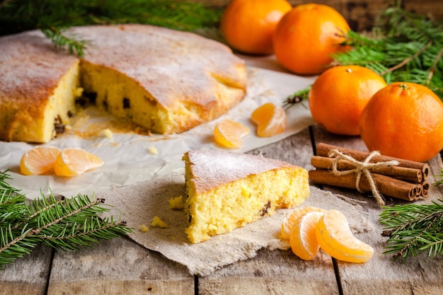 Trozo de bizcocho navideño con mandarinas y canela sobre un fondo rústico