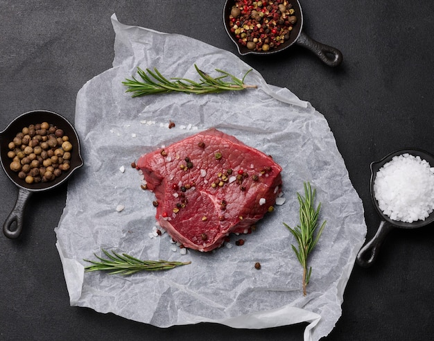 Un trozo de carne cruda con especias se encuentra en una vista superior de papel pergamino blanco