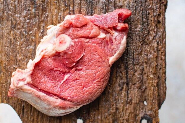 Foto trozo de carne cruda con hueso de ternera ossobuco, cordero o cerdo, abundante comida