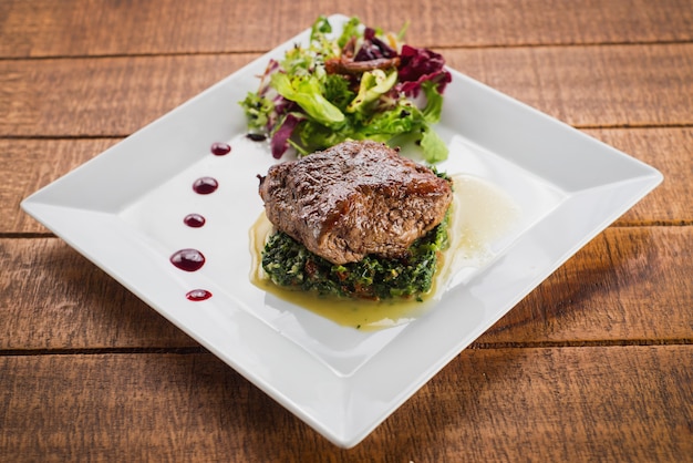 Trozo de carne frita con hierbas y especias en mesa de madera