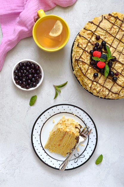 Un trozo de delicioso postre festivo en capas con hojaldre y natillas y una taza de té de limón