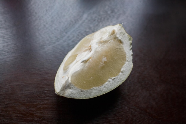 Un trozo de fruta de pomelo en una mesa de cocina oscura