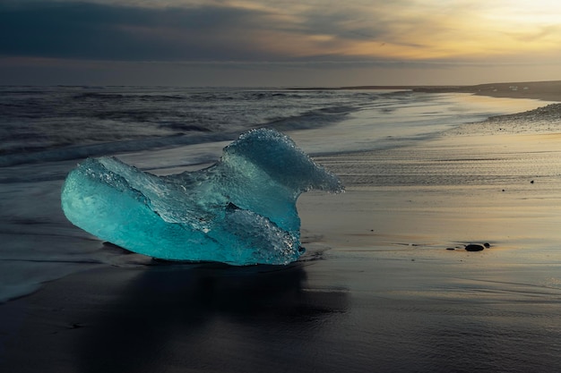 Foto un trozo de hielo en la playa al atardecer