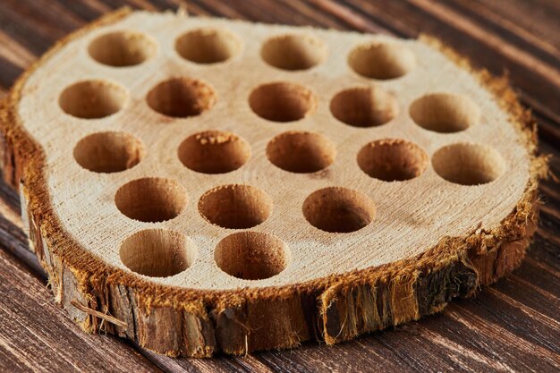 Trozo de madera de eucalipto con agujeros para inhalación de dolor de garganta sobre fondo de madera.