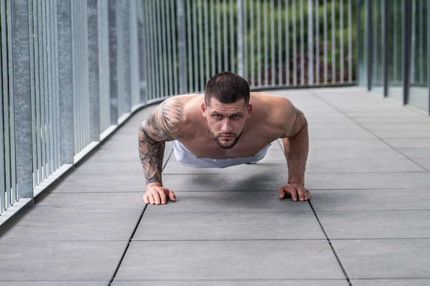 Trozo musculoso con posando en el gimnasio fitness modelo masculino cerca de equipo de gimnasio joven hombre musculoso entrenamiento sp