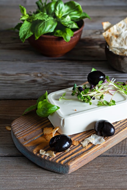 Un trozo de paneer de queso feta fresco con aceitunas, hierbas, especias y rebanadas de pan plano sin levadura